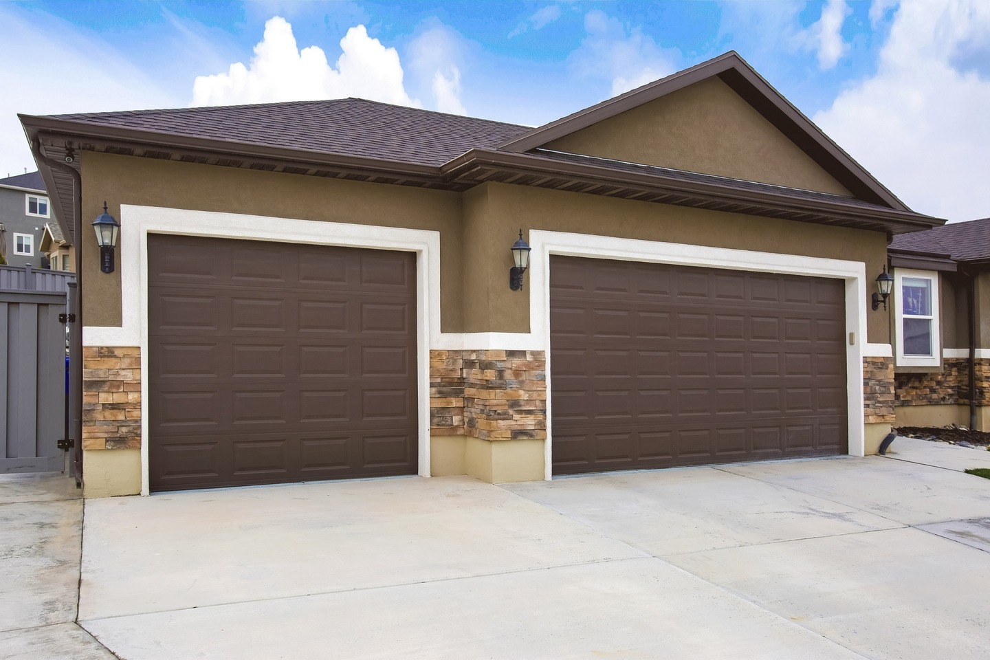 Exterior of a home with two brown garage doors against cloudy blue sky Brown Garage Doors Murrieta